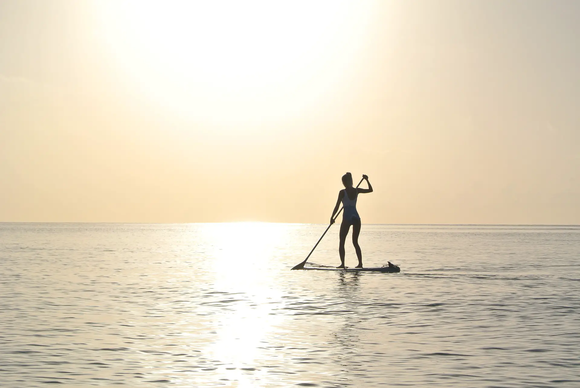 A person enjoys paddleboarding during the sunrise