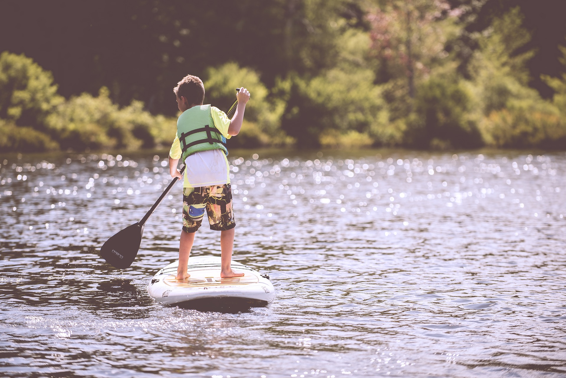 boy paddleboarding through the river