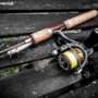 A spinning rod and reel sitting on a dock with a lure attached