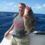 A man holding a red grouper offshore fishing