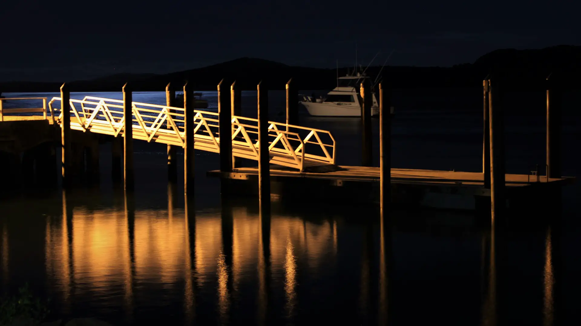 A boat docked at a marina at night