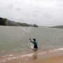 A person throwing a cast net to catch bait