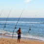 A man fishing from the beach with fishing rod holder sand pikes