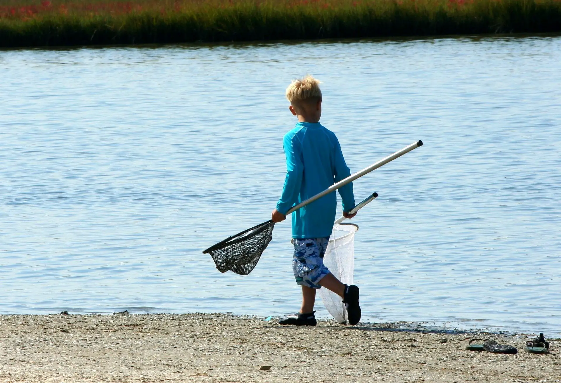 A boy carrying two fishing nets