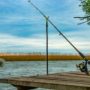 A fishing rod and reel perched on a dock